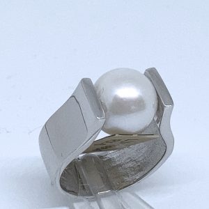 Sortija en plata rodiada en forma de "U", con perla cultivada esférica en el centro.